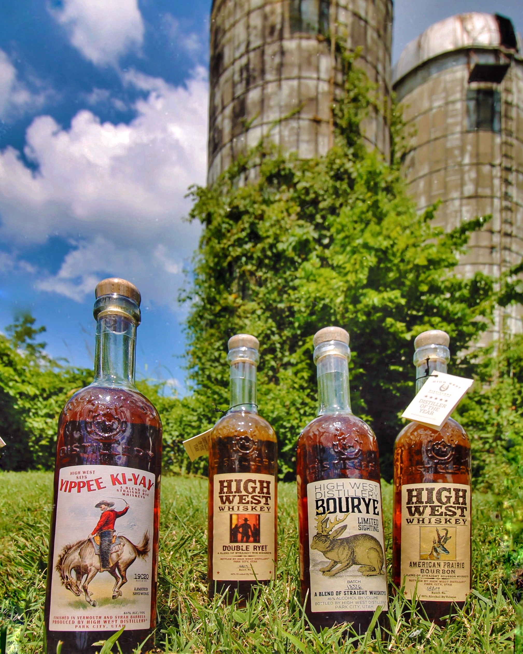 Four Whiskey Bottles In front of grain silos.