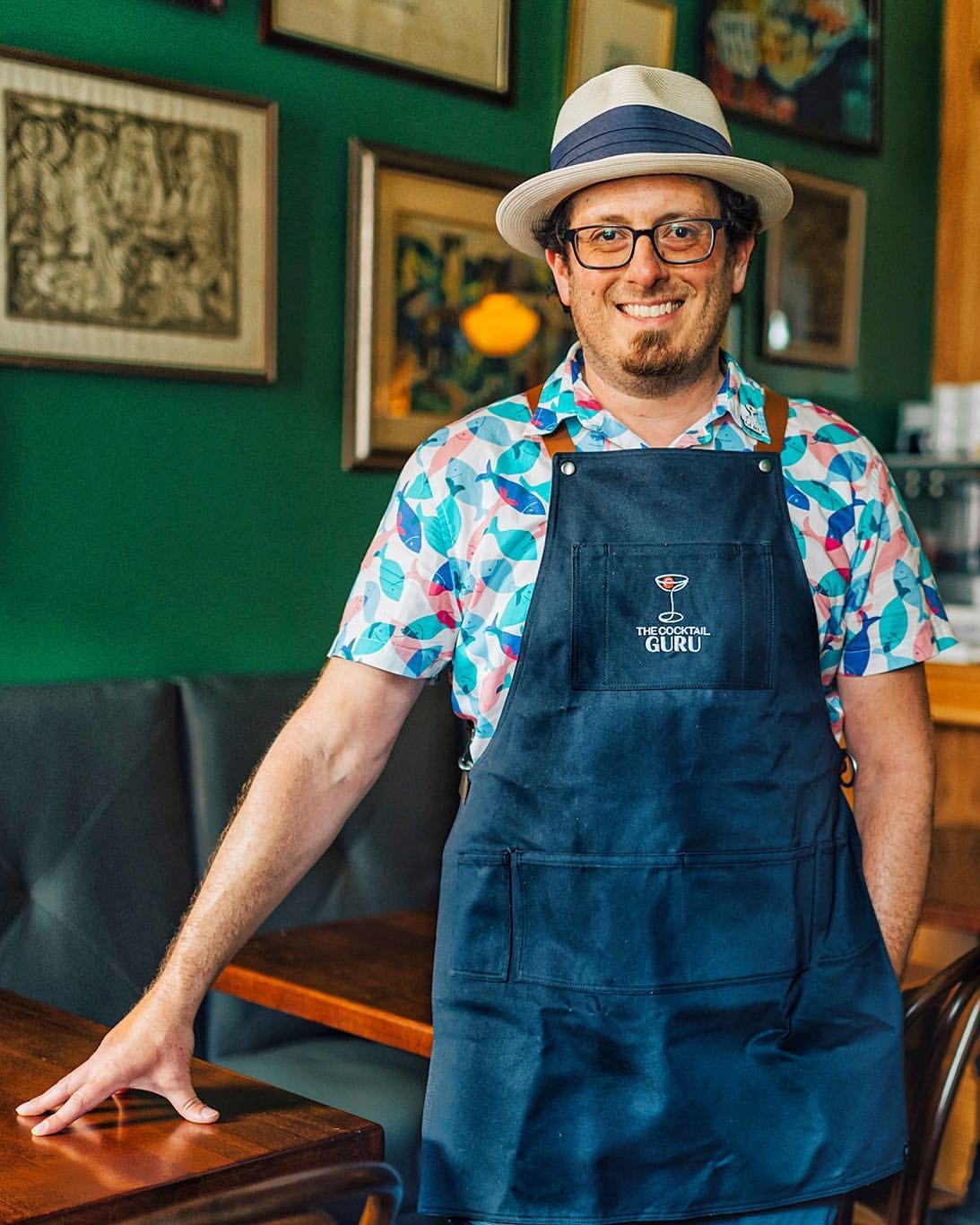 The Cocktail Guru standing in a bar with a blue canvas apron.