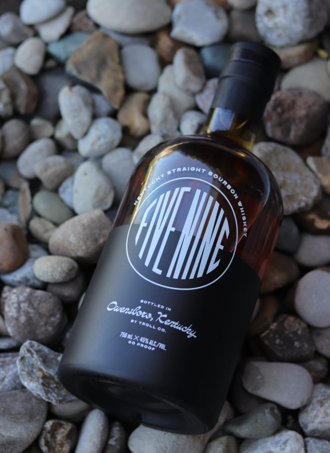 Bourbon bottle on rocks in a garden.