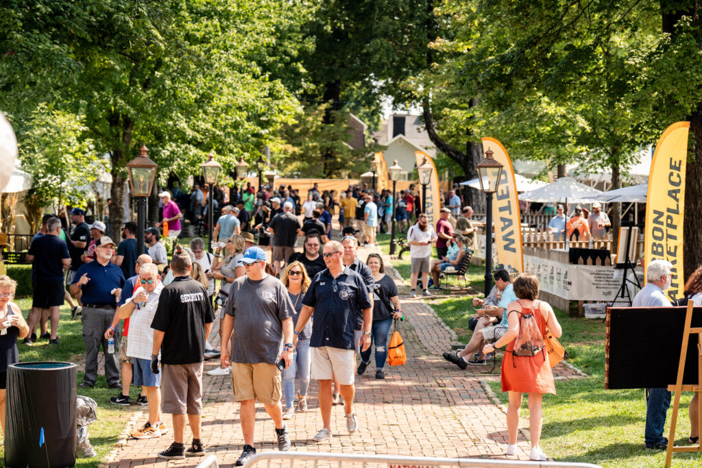 A brick sidewalk with a crowd of people at the Kentucky Bourbon Festival.