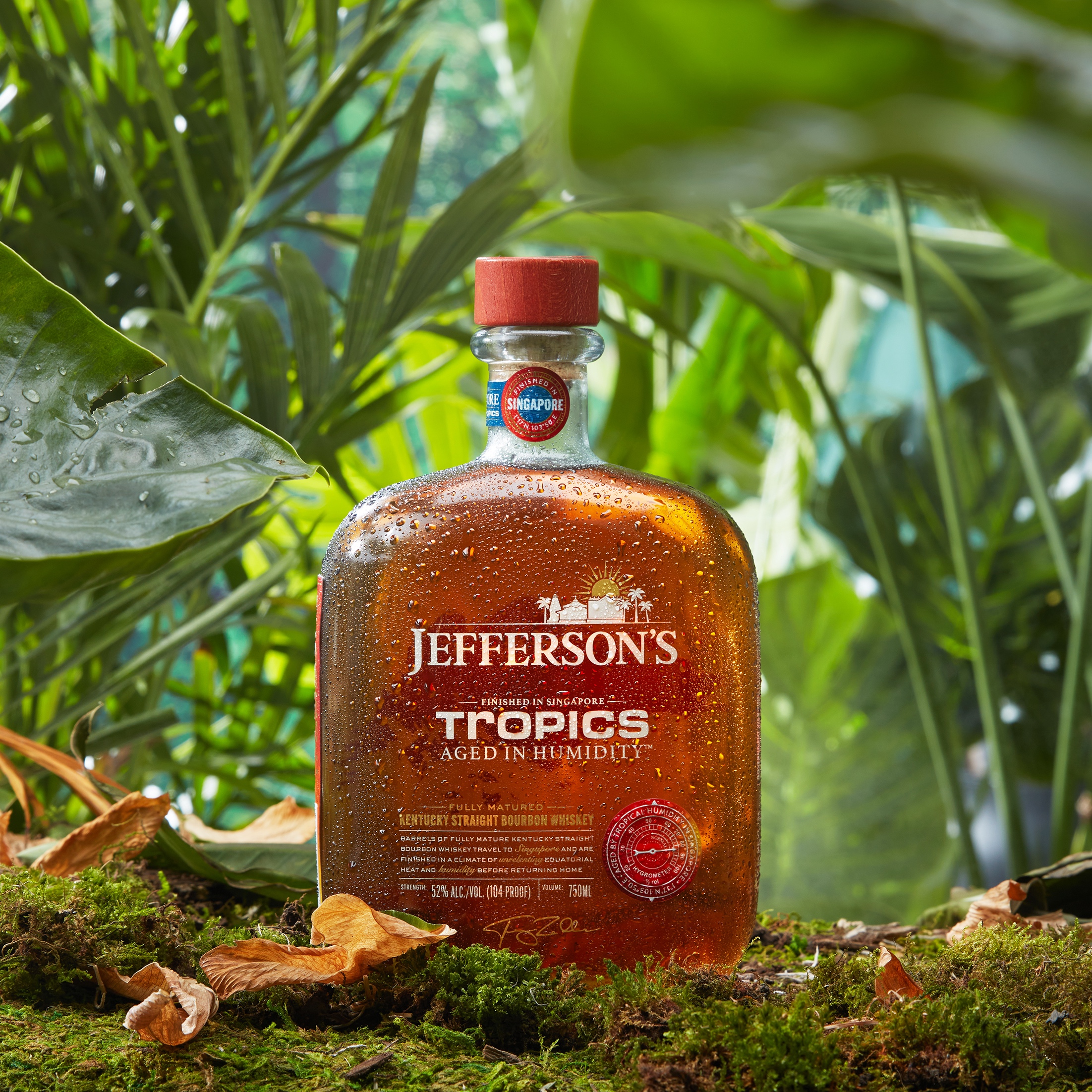 A bottle of Jefferson's Tropics Bourbon, Aged in Humidity, against a lush green backdrop.