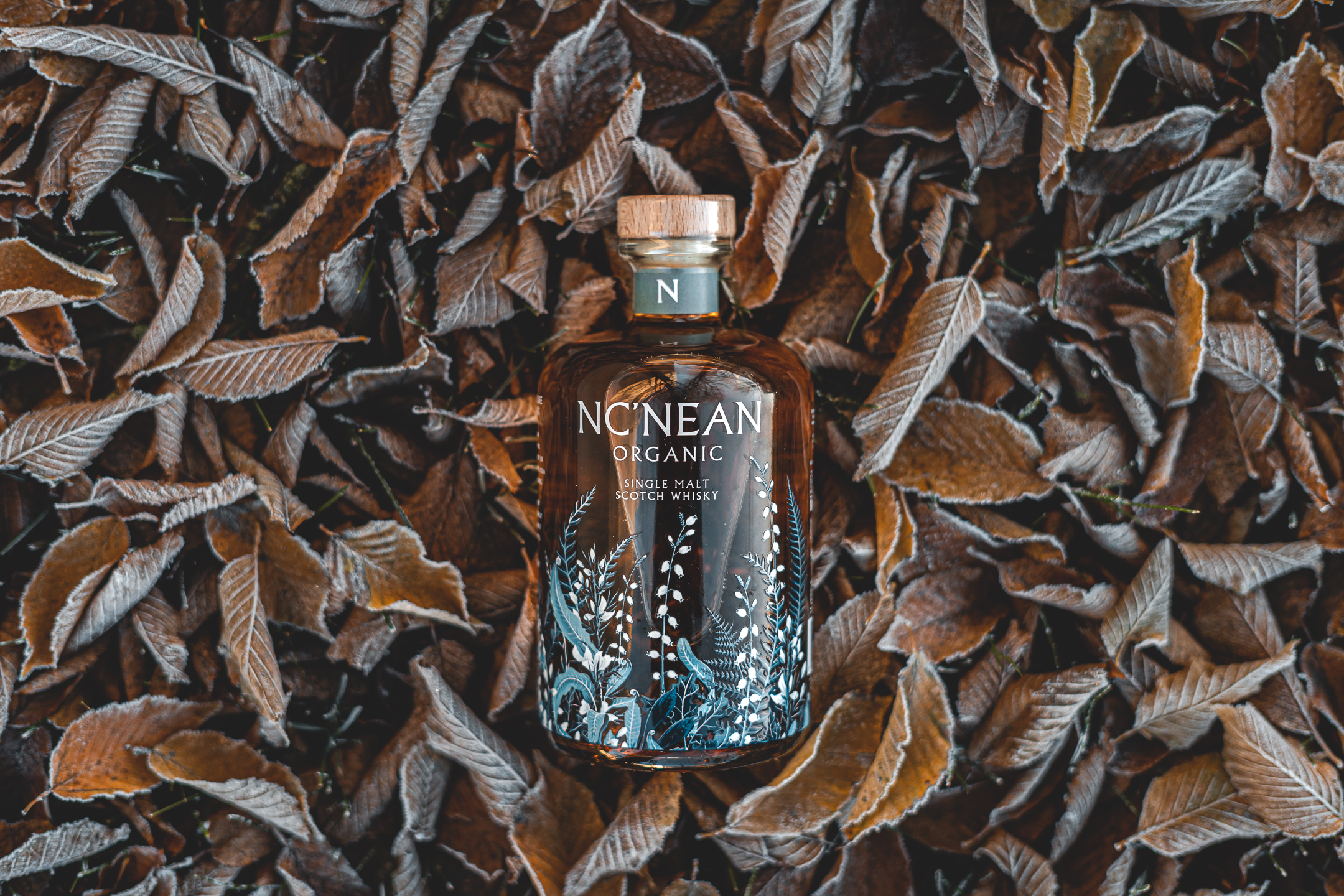 NC’NEAN Organic Single Malt Resting on a bed of fallen leaves.