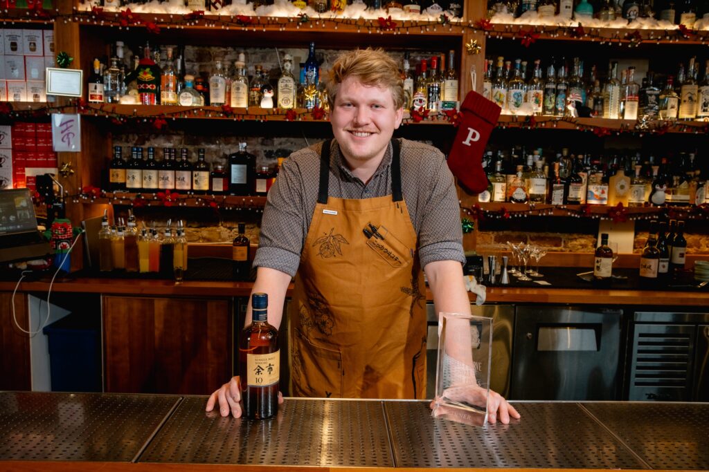 Evan Flynn with Nikka Whisky and bar behind hime.
