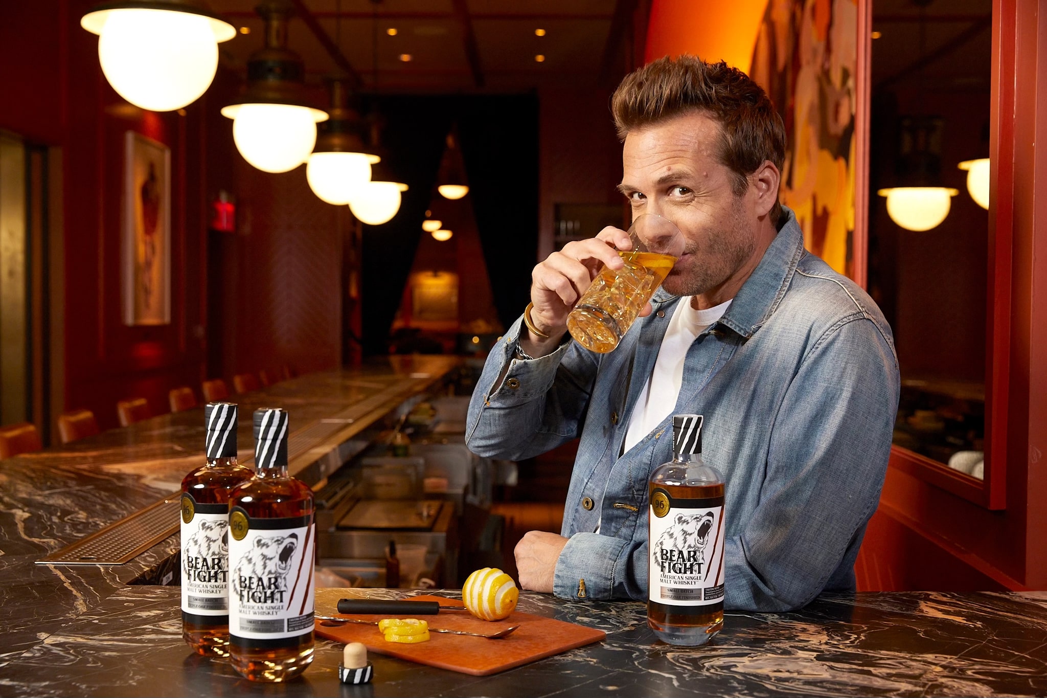 Man at a bar sipping a whiskey.